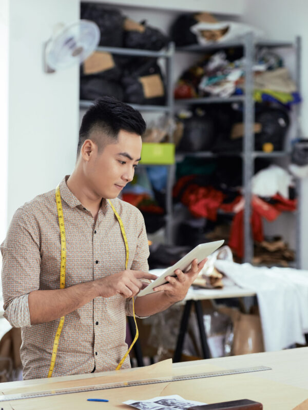 Designer using digital tablet for work Asian young male stylist standing and looking at digital tablet before begin to work